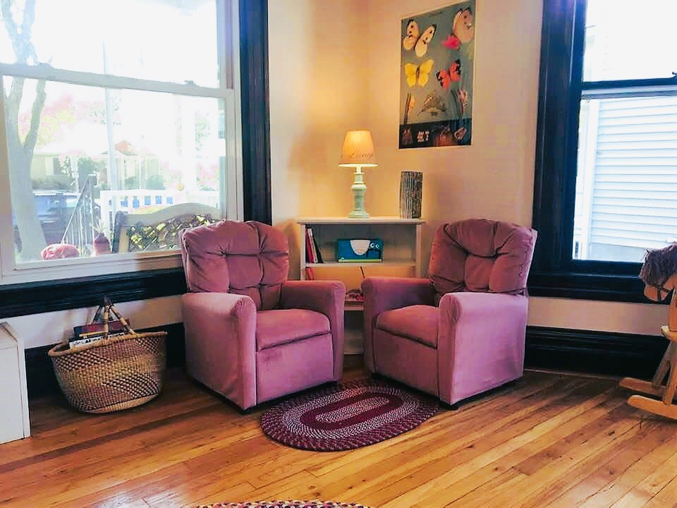 A corner with 2 plush chairs and books